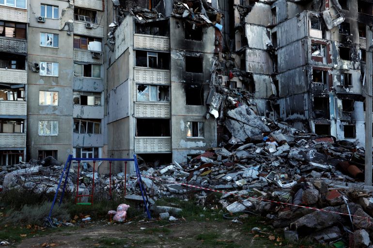 A pink teddy bear lies on the ground in front of residential apartments that were destroyed by Russian military strikes