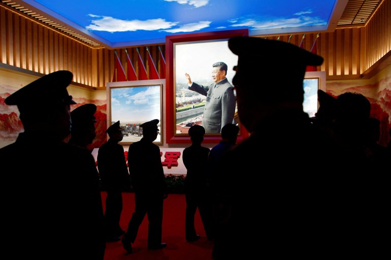 Soldiers walk past an image of Xi Jinping in a Mao suit and waving, at a military museum in Beijing.