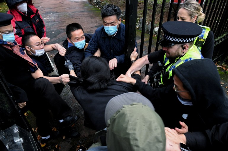 A policeman pulls a man from a group dragging him into the China consulate in Manchester after Hong Kong democracy protesters were attacked on Sunday.