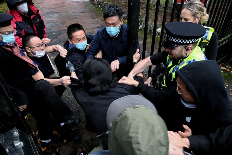 A policeman pulls a man from a group dragging him into the China consulate in Manchester after HK democracy protesters were attacked on SUnday