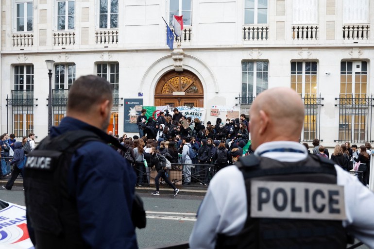 French police stand guard as students block the entrance of the Lycee Montaigne high school to protest as part of a nationwide day of strike in Paris