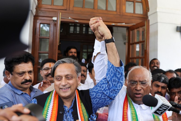 Mallikarjun Kharge, newly elected president of the Congress party, India's main opposition party, raises his hand with party colleague Shashi Tharoor at Kharge’s residence in New Delhi, India,