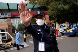 A police officer attempts to block the photographers view outside a residential compound after it was locked down due to a COVID-19 outbreak in Beijing, on October 20, 2022 [Thomas Peter/Reuters]