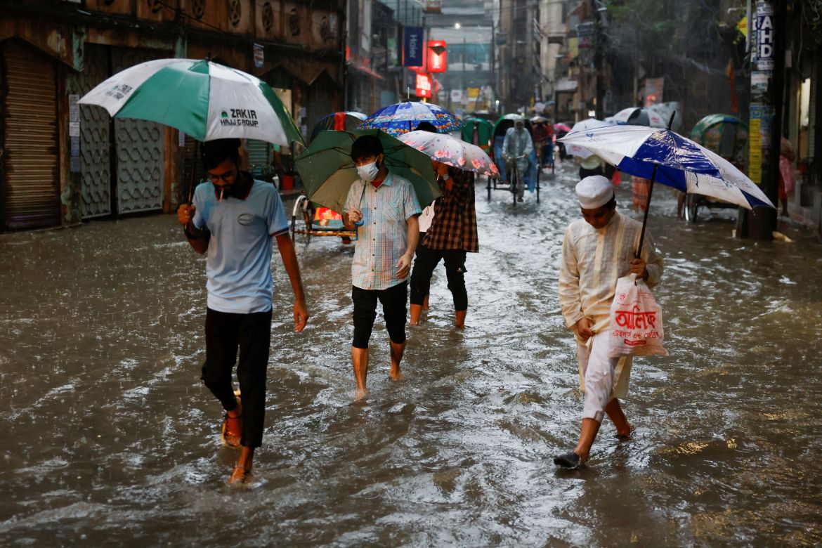 People wade through a flooded street, amid continuous rain before the Cyclone Sitrang hits the country in Dhaka, Bangladesh, October 24, 2022.
