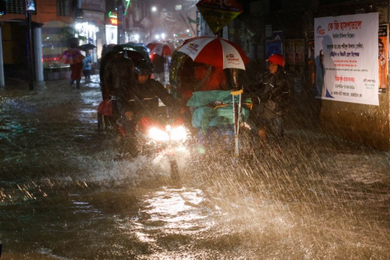 People ride rickshaws and motorcycles on a flooded road, amid continuous rain before Cyclone Sitrang hits the country in Dhaka, Bangladesh, October 24, 2022