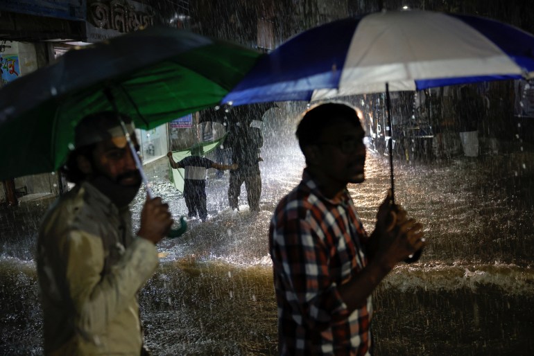 People wade through a flooded street amid continuous rain before Cyclone Sitrang makes landfall in the country in Dhaka, Bangladesh, October 24, 2022