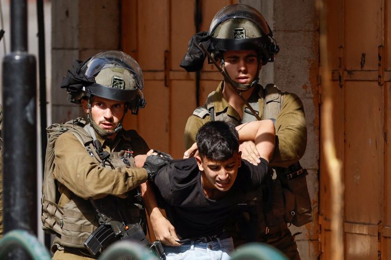 Israeli soldiers detain an injured Palestinian during clashes