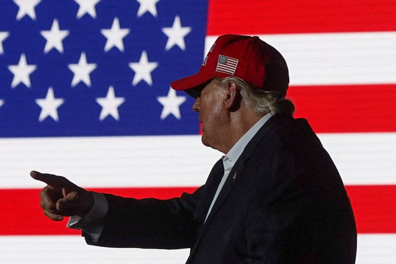 Profile of Donald Trump pointing while wearing MAGA hat