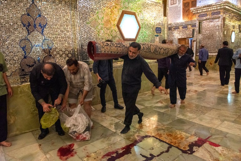 Shah Cheragh Shrine personnel clean after an attack in Shiraz, Iran