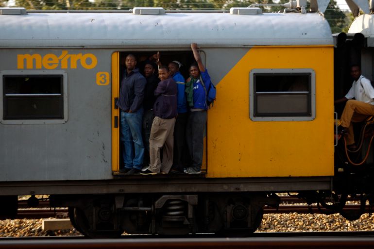 Rail commuters stand on the front of a moving train in Soweto, South Africa