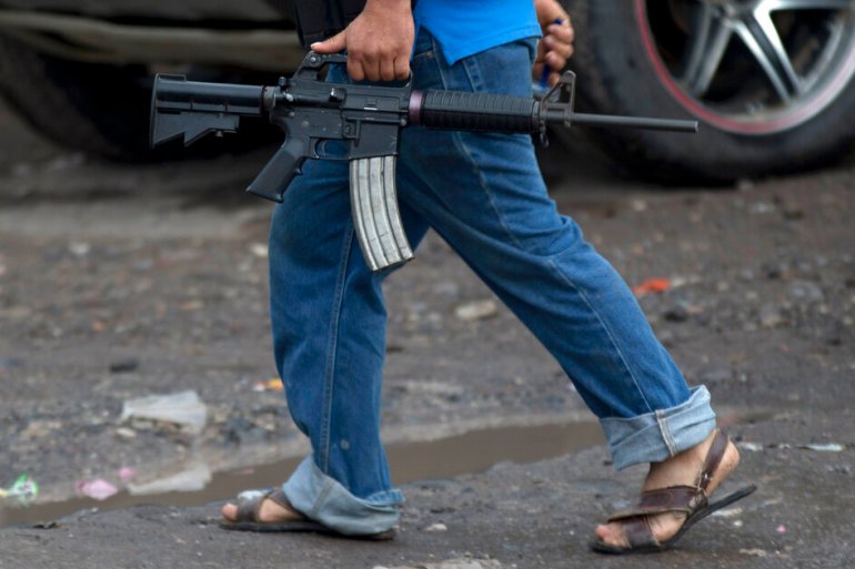 A man carries his weapon at a checkpoint set up by a self-defence group at the entrance to the town of Antunez, Mexico, in 2014 [File: Eduardo Verdugo/AP]