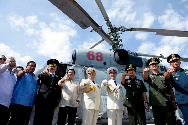 Then-Philippine President Rodrigo Duterte (fourth left), gestures with Russian ambassador to the Philippines Igor Khovaev (third left), and Russia's Rear Admiral Eduard Mikhailov (fifth left), with other Philippine and Russian officials in front of an anti-submarine helicopter on the anti-submarine ship Admiral Tributs in Manila, Philippines in 2017 [Noel Celis/Pool Photo via AP]