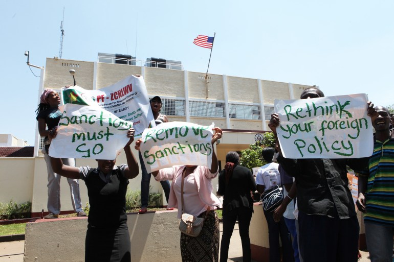 A group of people supporting Zanu pf political party hold placards outside the American Embassy in Harare, Zimbabwe, demanding the US to remove sanctions against Zanu pf, Wednesday, Oct. 30, 2013. The group of demonstrators are calling on the American government to remove trade sanctions and travel restrictions imposed on some Zanu pf party members. (AP Photo/Tsvangirayi Mukwazhi)