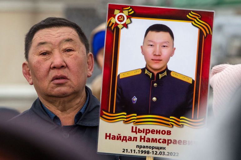 A man holds portrait of Russian Army officer Naidal Tsyrenov, who was killed during fighting in Ukraine, during the Immortal Regiment march in Ulan-Ude, the regional capital of Buryatia, a region near the Russia-Mongolia border, Russia, Monday, May 9, 2022, marking the 77th anniversary of the end of World War II. (AP Photo)