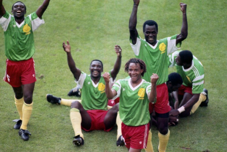 Members of the Cameroon national soccer team raise their arms and jubilate