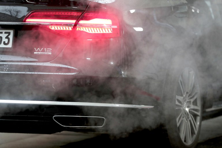 A luxury Audi car is surrounded by exhaust gases as it is parked with a running engine in front of the Chancellery in Berlin