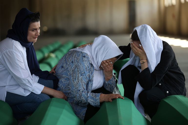Bosnian muslim women mourn next to the coffin containing remains of their family member who is among 50 newly identified victims of Srebrenica Genocide in Potocari, Bosnia, Sunday, July 10, 2022. Thousands converge on the eastern Bosnian town of Srebrenica to commemorate the 27th anniversary on Monday of Europe's only acknowledged genocide since World War II. (AP Photo/Armin Durgut)