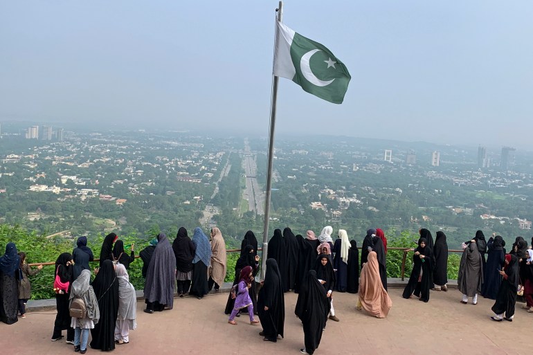 A Pakistani flag flies on a lookout as women take in the view of Islamabad, Pakistan, Wednesday, July 27, 2022. (AP Photo/Rahmat Gul)