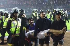 Fans carry an injured man following clashes during a football match at Kanjuruhan Stadium in Malang, East Java, Indonesia [Yudha Prabowo/AP Photo]