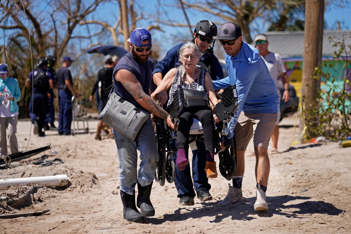 Rescuers help evacuate Suzanne Tomlinson, a resident who rode out the storm, as they carry her to a waiting boat in the aftermath of Hurricane Ian on Pine Island in Florida's Lee County