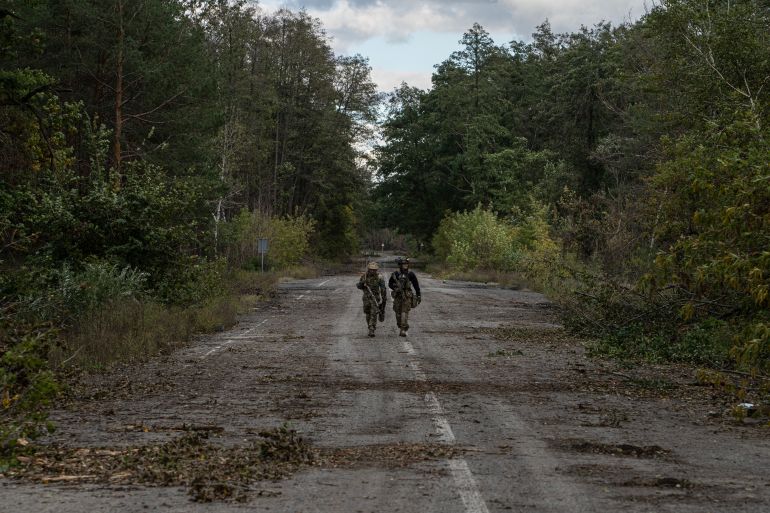 Ukrainian servicemen patrol a road in Lyman