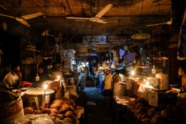Shopkeepers light candles during power failure in capital Dhaka [Mahmud Hossain Opu/AP]