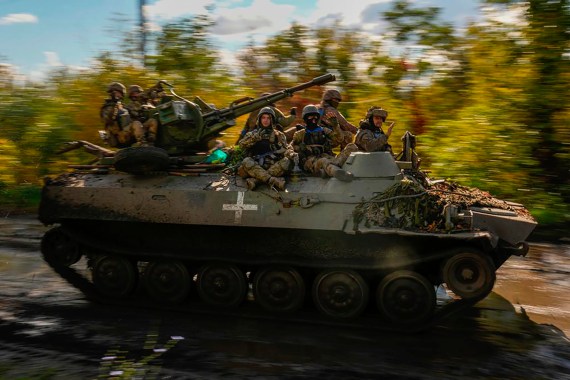 Ukrainian soldiers sit on an armoured vehicle as they drive on a road between Izyum and Lyman in Ukraine.