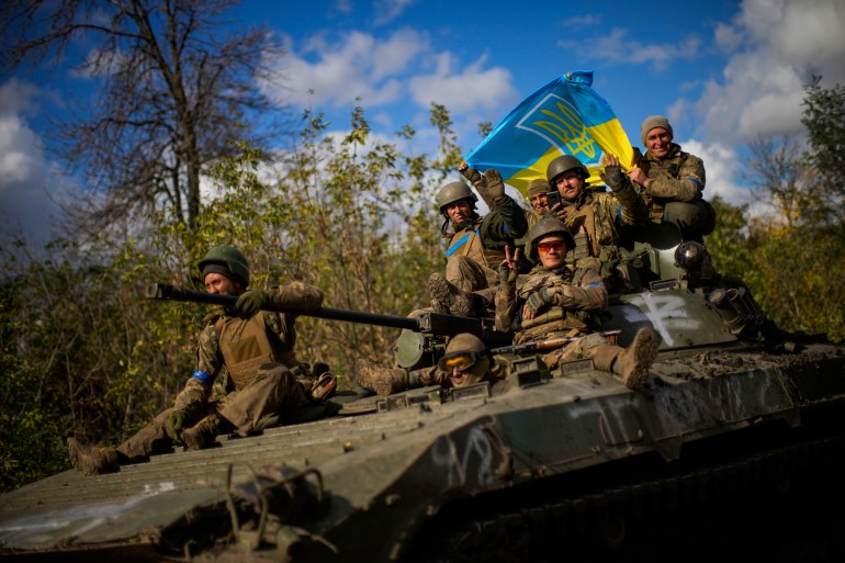 Soldados ucranianos sentados em um veículo blindado enquanto dirigem em uma estrada entre Izium e Lyman na Ucrânia, 4 de outubro de 2022