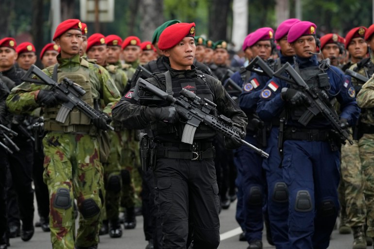 Troops from Indonesia's elite Kopassus unit in their distinctive red berets march with their weapons
