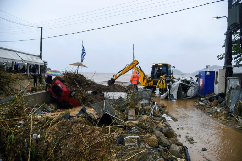 Workers try to clear an area following heavy thunderstorms, in the village of Agia Pelagia, on the island of Crete, Greece, Saturday, Oct. 15, 2022. It has been reported that at least one person has died with others missing due to the severe flooding. (AP Photo/Harry Nakos)