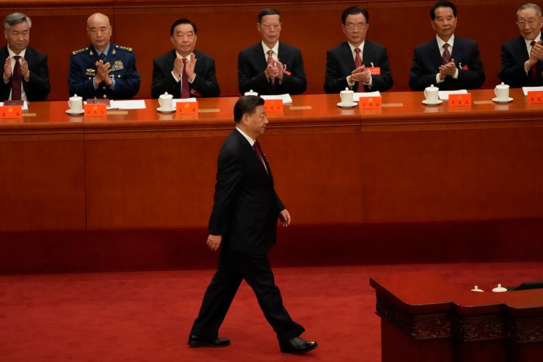 Xi Jiinping walks to the lectern in the Great Hall of the People in Beijing with party officials seated behind him