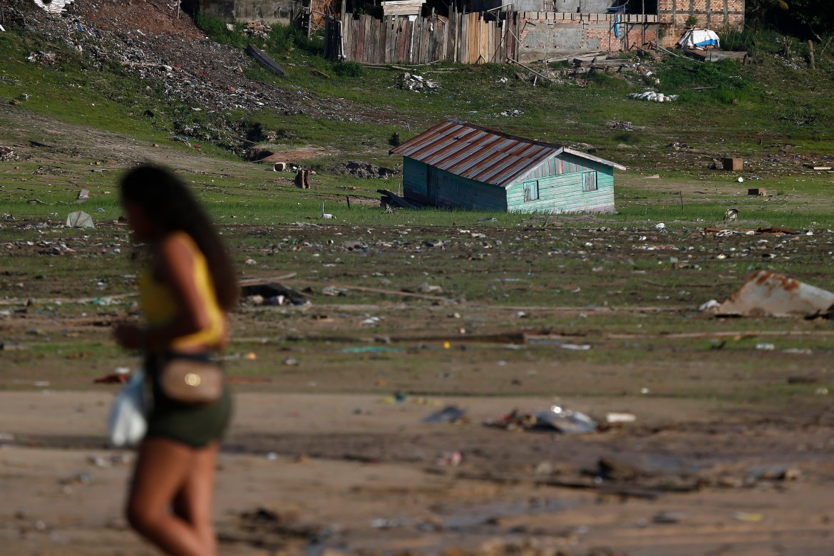 A woman walks near a houseboat impacted by the drought near the Solimões River, in Tefe, Amazonas state, Brazil