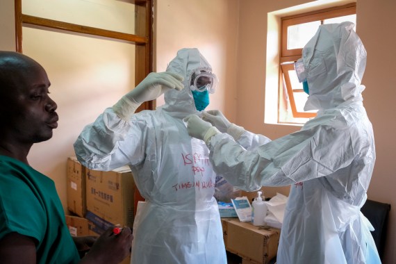Doctors put on protective equipment as they prepare to visit a patient who was in contact with an Ebola victim, in the isolation section of Entebbe Regional Referral Hospital in Entebbe, Uganda