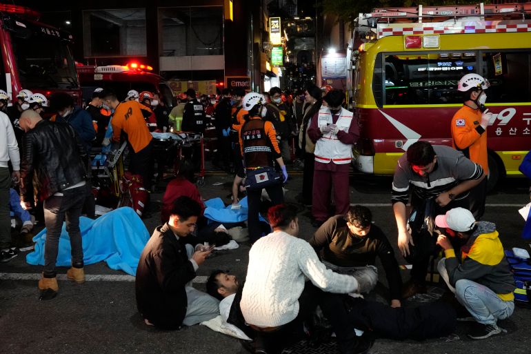 Rescue workers and firefighters try to help injured people near the scene of a crowd surge in Seoul, South Korea, Sunday, Oct. 30, 2022.