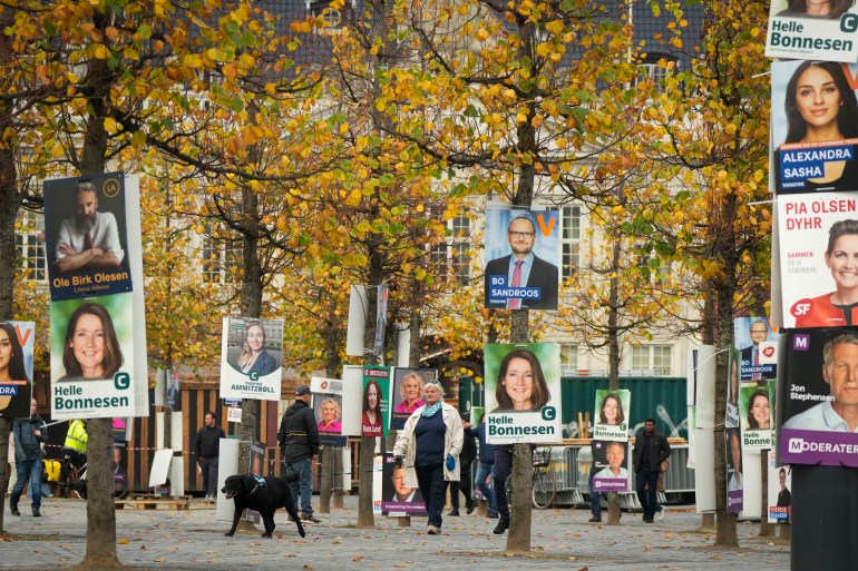 People pass by election campaign posters in Copenhagen, Denmark, Sunday, Oct. 30, 2022, ahead of the general election scheduled for Nov. 1, 2022. Denmark's election on Tuesday is expected to change its political landscape, with new parties hoping to enter parliament and others seeing their support dwindle. A former prime minister who left his party to create a new one this year could end up as a kingmaker, with his votes being needed to form a new government. (AP Photo/Sergei Grits)