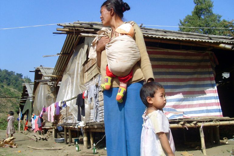 A Kachin refugee woman with children stands outside huts at the Hpun Lum Yang camp for displaced poeple near Laiza in northern Myanmar in 2013 [File: Yadana Htun/AP]
