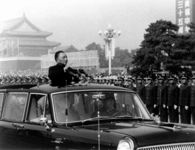 Black and white photo showing Deng Xiaoping reviewing troops in Tiananmen Square from a "Hongqi" convertible limousine.