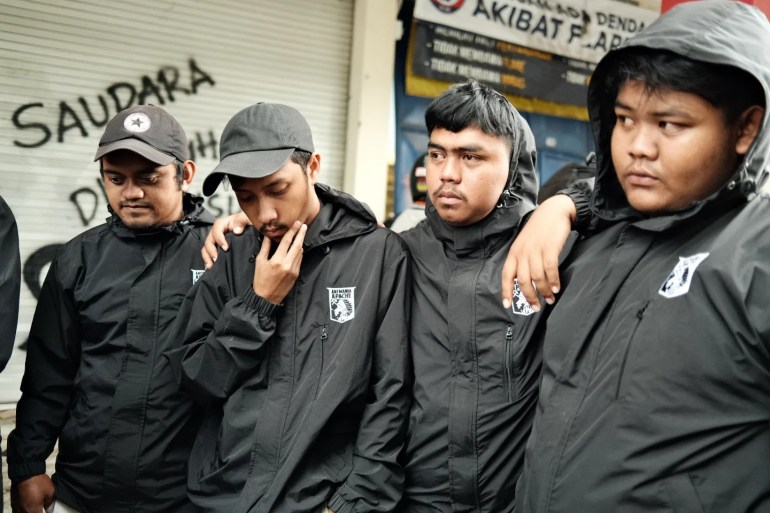 Four young men in black look sombre as they remember those killed in the Malang stadium