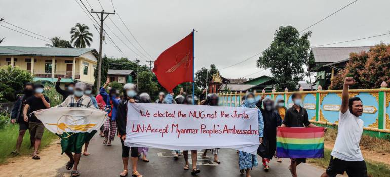Protesters march with a banner saying 'We elected the NUG, not the junta. UN accept Myanmar People's Ambassador'.