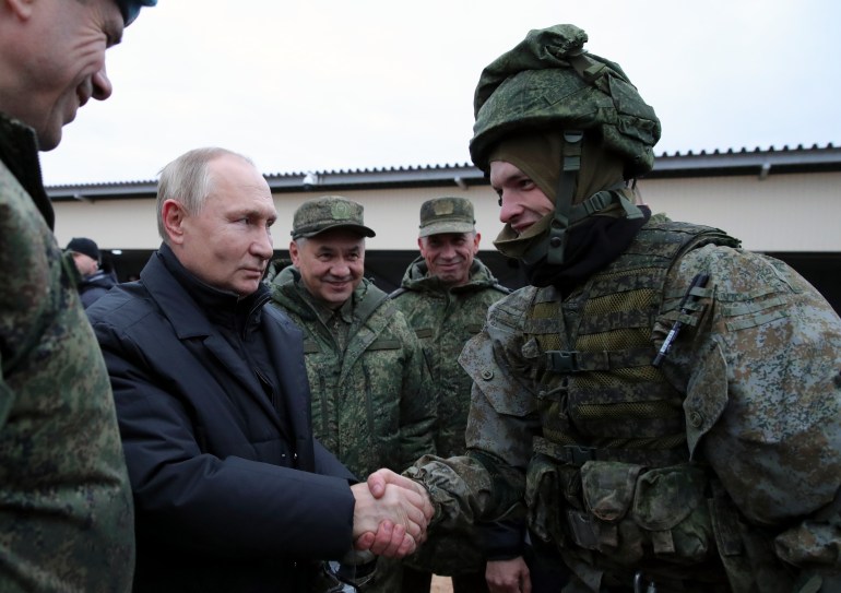 Russian President Vladimir Putin shakes the hand of a service member as Russian Defense Minister Sergei Shoigu looks at other officers at a training ground in the Ryazan region, Russia.