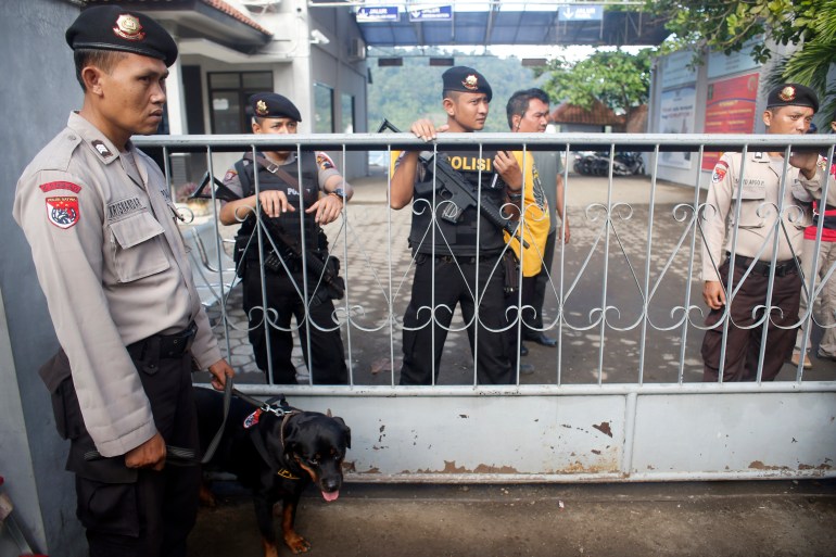 Police and soldiers stand guard behind a metal gate at the port that is the entry point to Indonesia's prison island of Nusakambangan.
