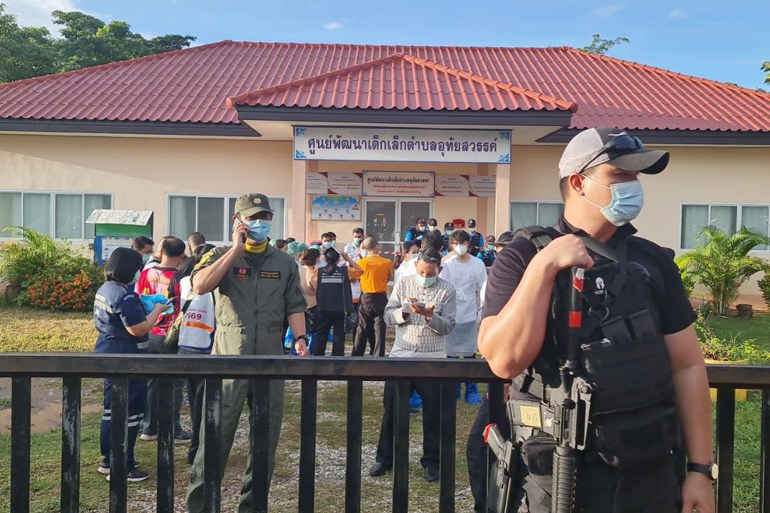 Armed police officer standing guard as relatives of the victims of a mass shooting gather at a childcare center in Nong Bua Lamphu province, northeastern Thailand
