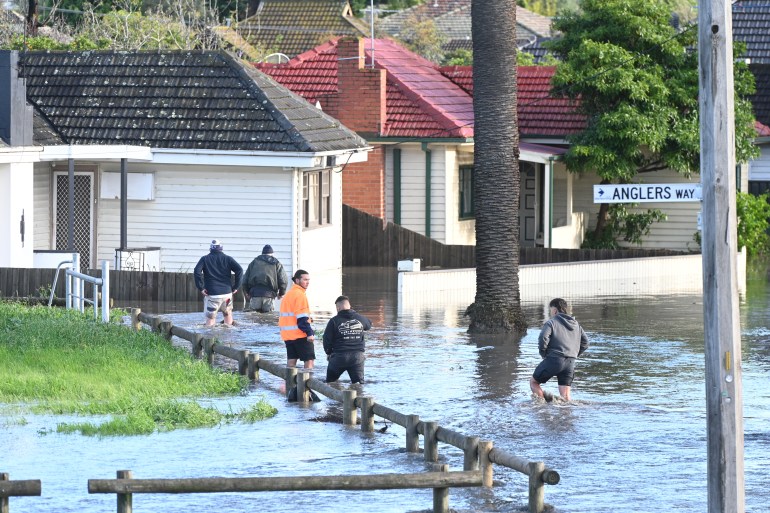People walking next to a flooded field with houses behind in the suburb of Maribyrnong in Melbourne, Australia.