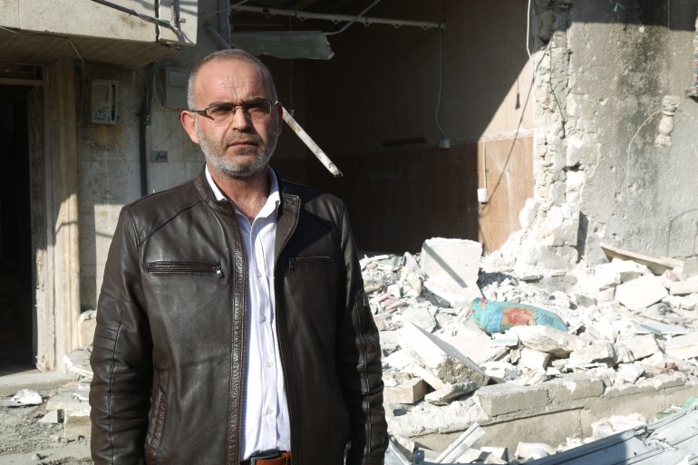 Hassan al-Khatib stands in front of rubble