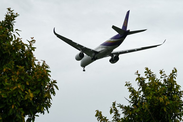A Thai Airwats plane coming into land above tree tops at Changi airport in Singapore