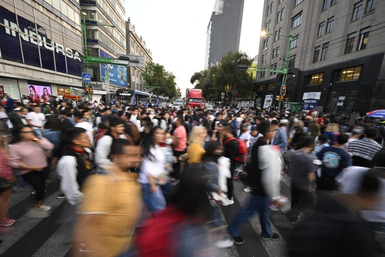 People walk at the crossing of Eje Central and Madero streets in downtown Mexico City