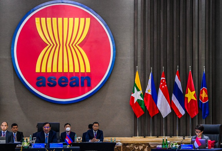 وزرای خارجه پشت میز بلندی نشسته اند که یک پوستر گرد بزرگ ASEAN بالای آن قرار دارد