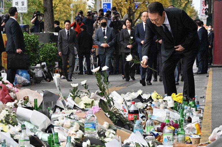 South Korean President Yoon Suk-yeol arranges flowers at a makeshift memorial for the victims of the deadly Halloween festival, outside a subway station in Itaewon district, Seoul on November 1, 2022.