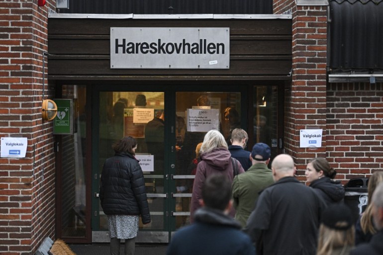 People arrive to cast their vote at a polling center located at the Hareskovhallen sports hall located in Vaerlose, near Copenhagen, on November 1, 2022 during the general elections in Denmark