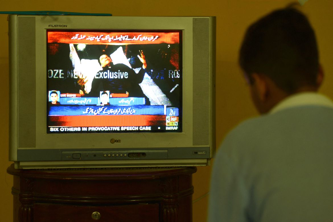 A boy watches a television channel showing the news of Pakistan's former prime minister Imran Khan